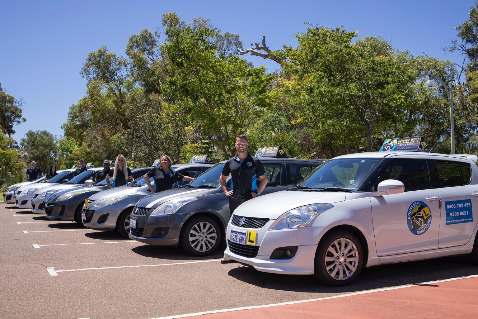 Driving West driving instructors beside the lineup of branded learner cars