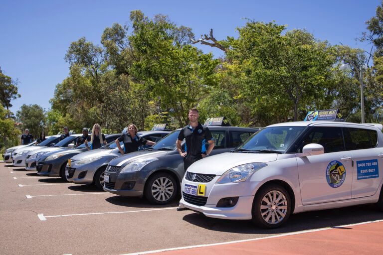 Driving West driving instructors standing beside their branded learner cars
